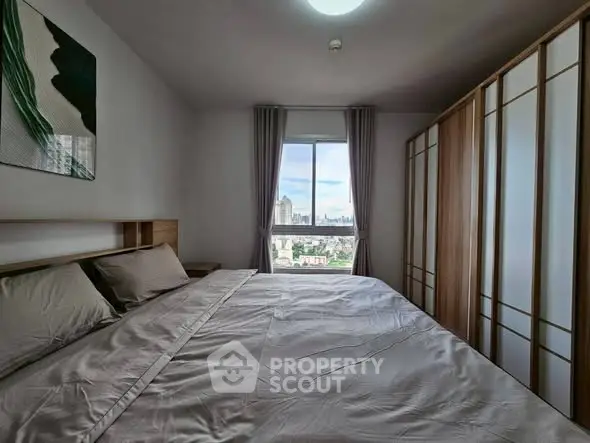 Spacious bedroom with city view, modern wardrobe, and elegant decor.