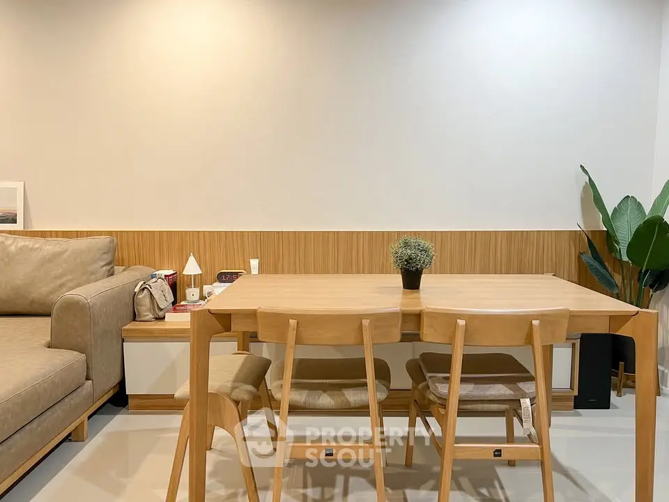 Modern dining area with wooden table and chairs, cozy sofa, and stylish decor in a contemporary apartment.
