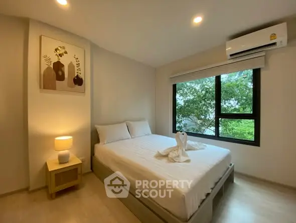 Cozy bedroom with modern decor and large window offering serene views, perfect for relaxation.