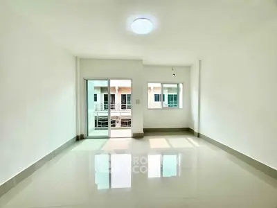 Spacious and bright living room with large windows and balcony access in modern apartment.