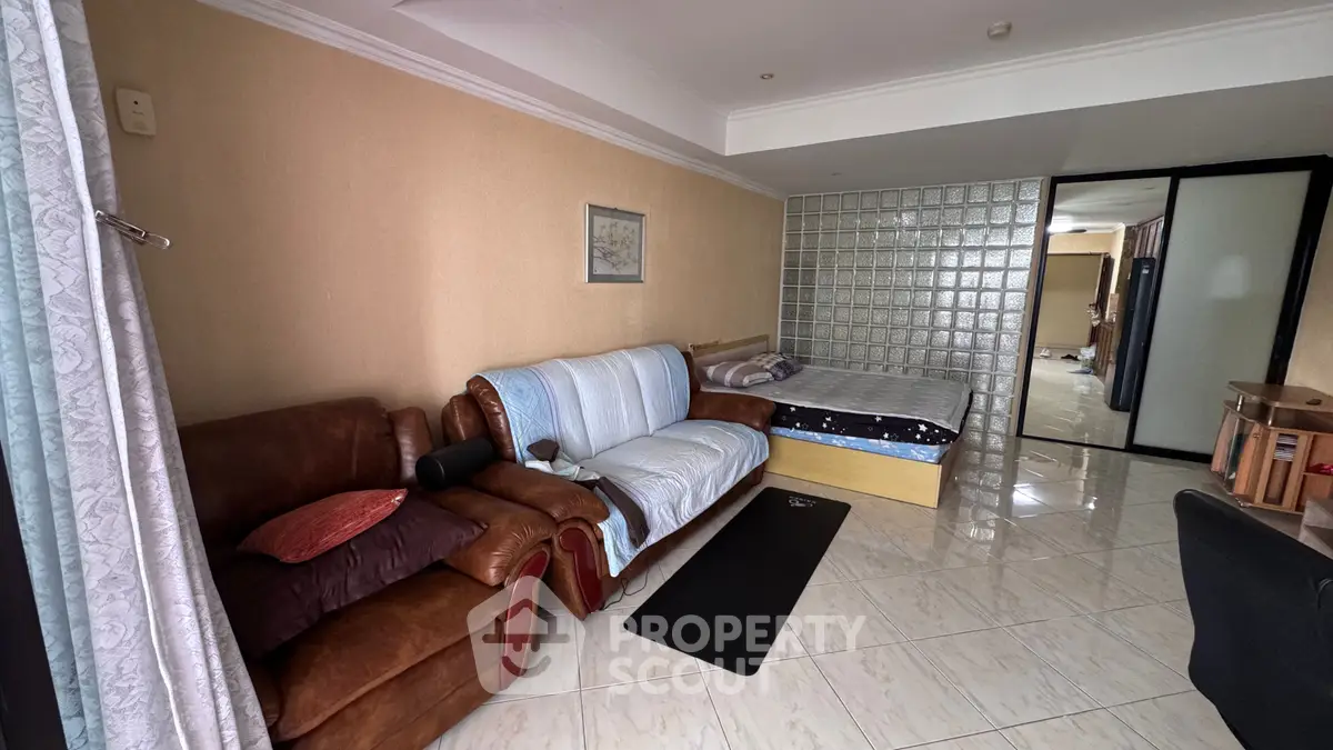 Spacious studio apartment with cozy living area and bed, featuring modern furnishings and tiled flooring.
