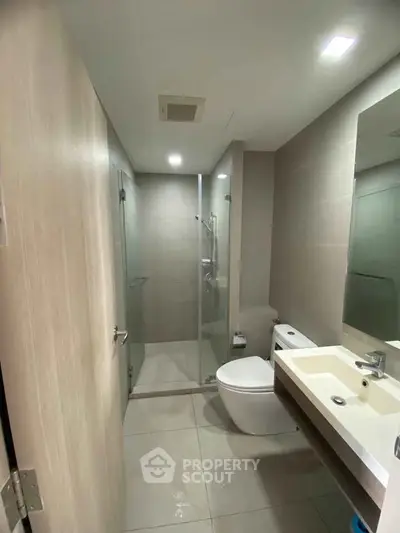 Modern bathroom with glass shower and sleek fixtures in a contemporary apartment.