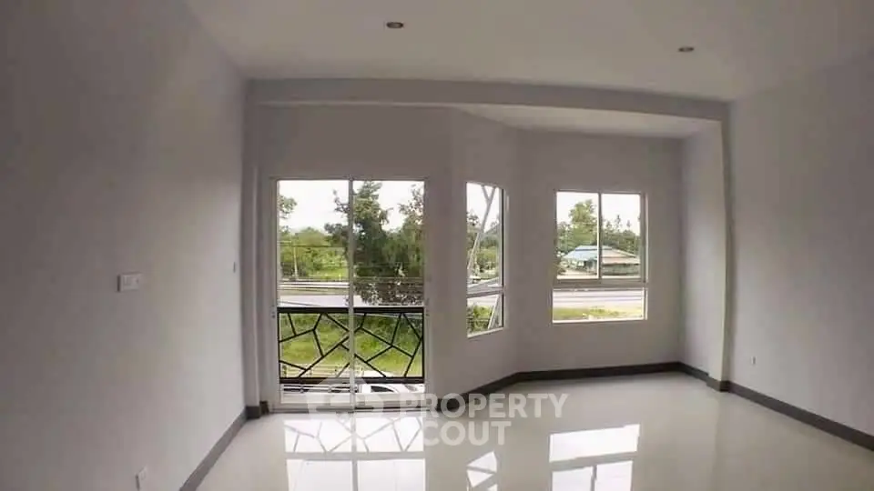 Spacious room with large windows and balcony overlooking greenery, perfect for natural light lovers.