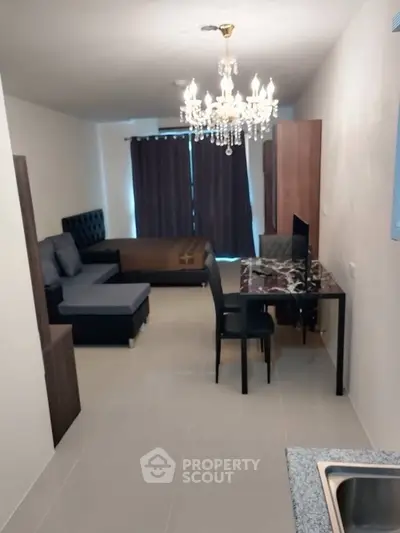 Modern studio apartment with elegant chandelier and cozy living area