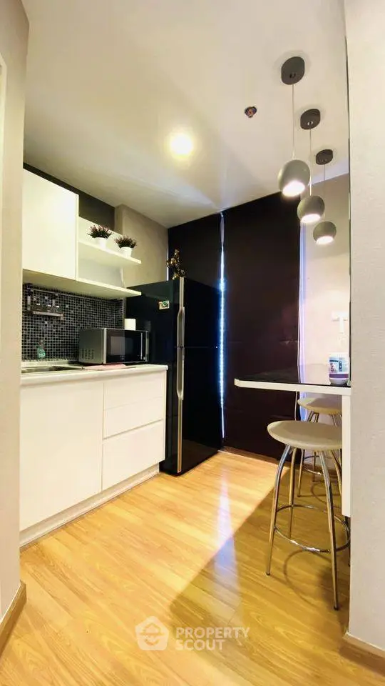 Modern kitchen with sleek black fridge and stylish lighting