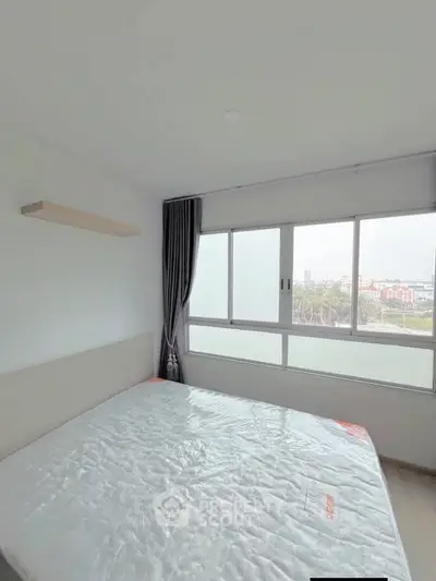 Bright bedroom with large window and modern decor, offering a serene view.