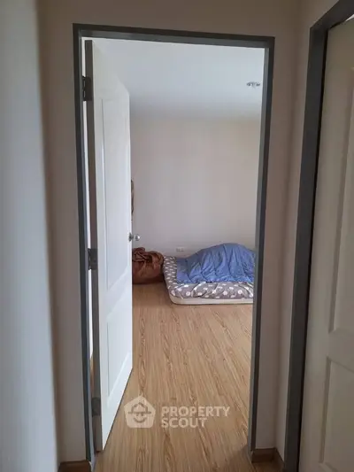 Minimalist bedroom with wooden flooring and simple bedding, perfect for cozy living.