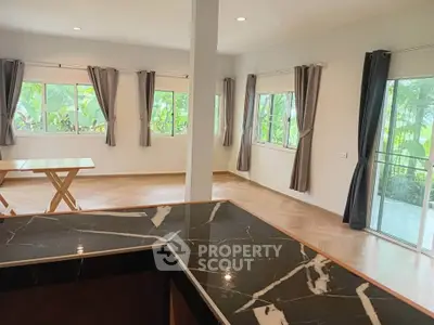 Spacious open-plan living area with large windows and elegant marble countertop, perfect for modern living.
