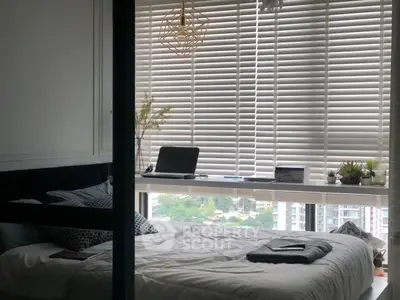 Modern bedroom with large window and city view, featuring stylish decor and natural light.
