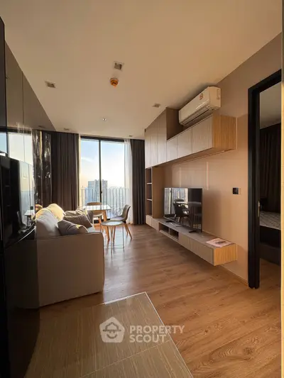Modern living room with large windows and city view, featuring stylish furniture and wooden flooring.