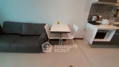 Modern living room with sleek sofa and compact dining area in stylish apartment.