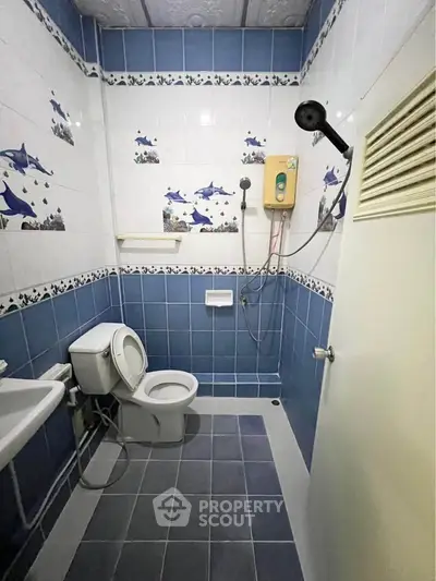 Charming blue-tiled bathroom with dolphin-themed decor and modern shower amenities.