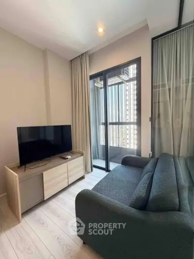 Cozy living room with modern sofa, TV, and access to a small balcony.