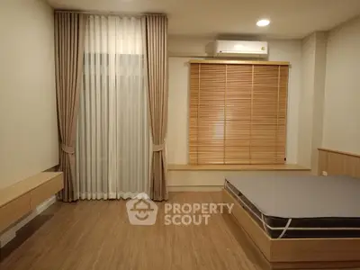 Modern minimalist bedroom with wooden flooring and stylish window treatments.