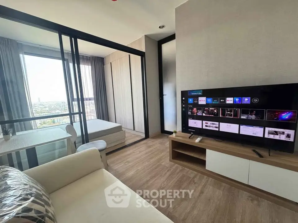 Modern living room with TV and view of bedroom through glass partition in stylish apartment.