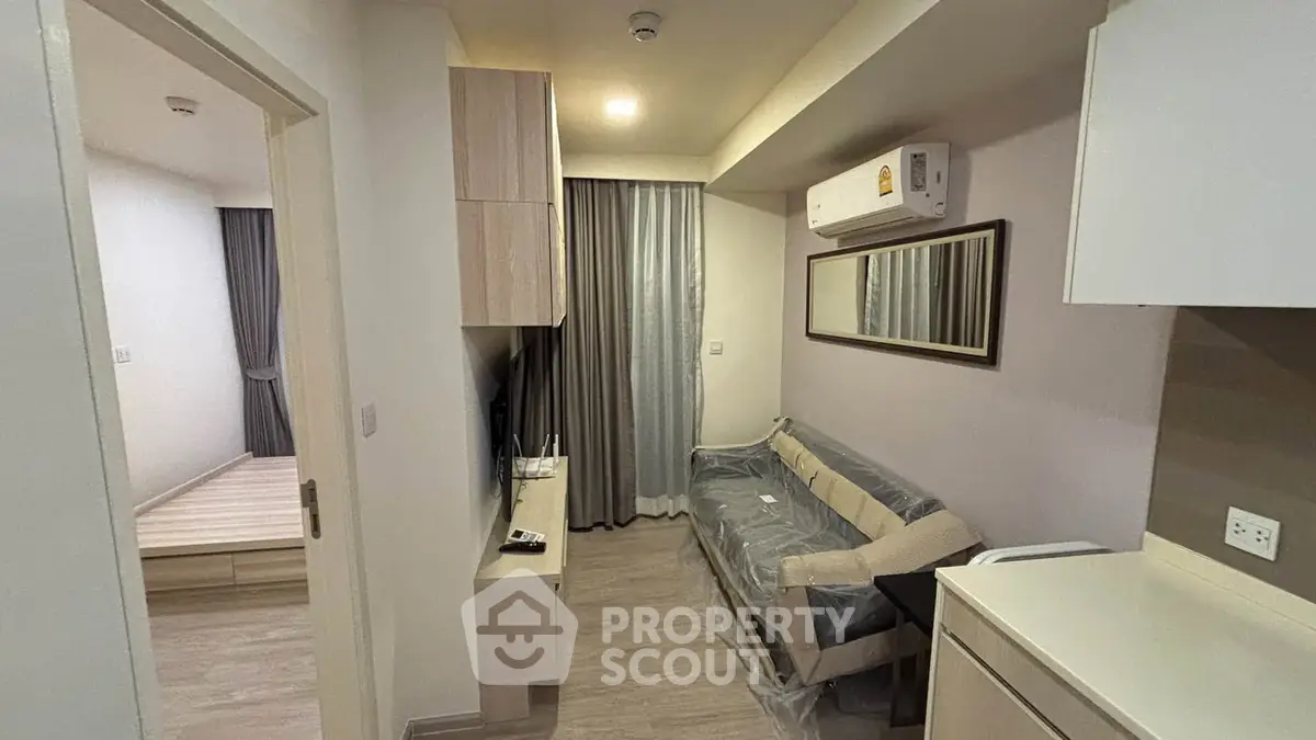 Modern apartment interior with cozy living room and adjacent bedroom, featuring sleek furniture and neutral tones.