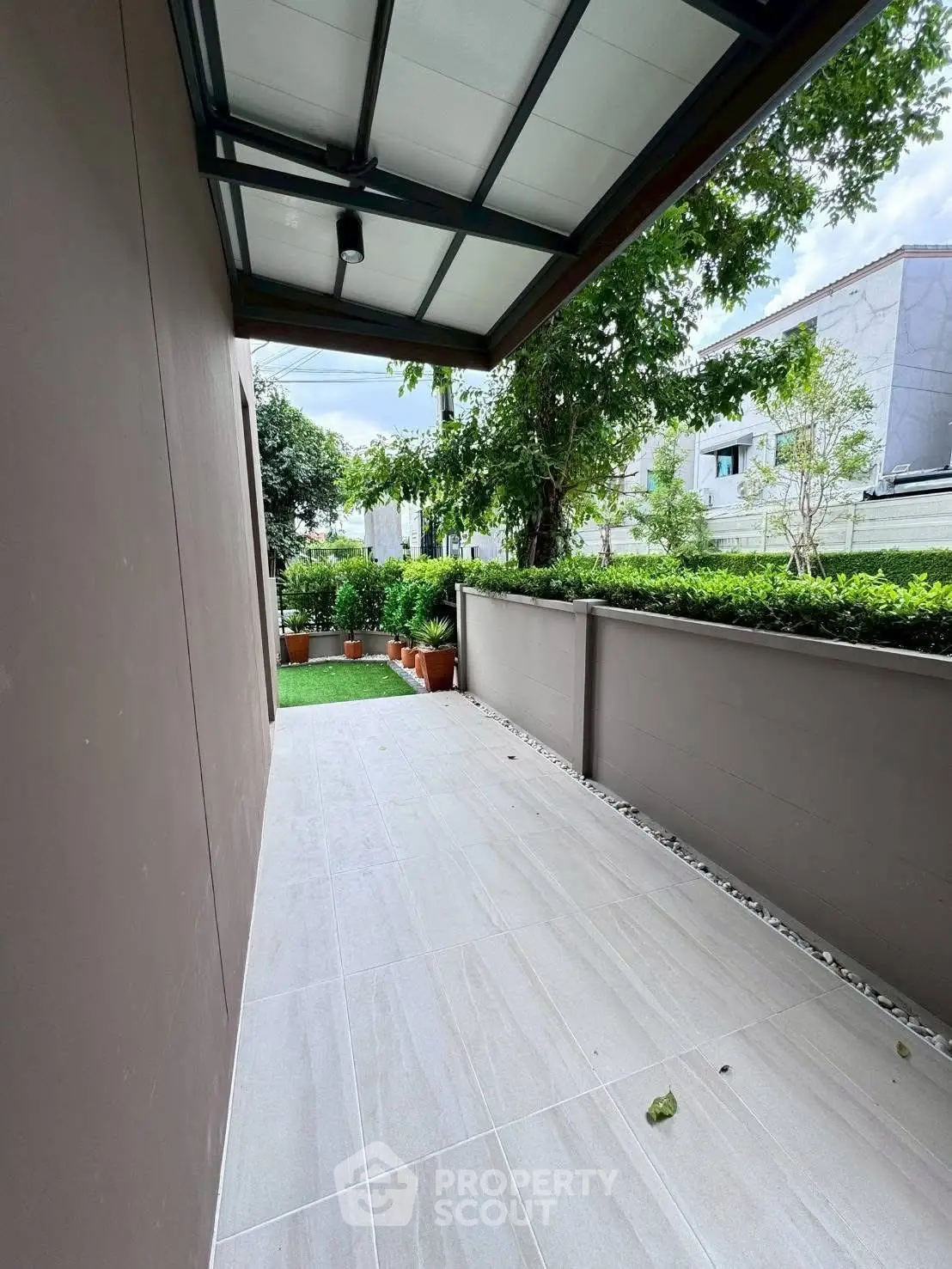 Charming outdoor patio with lush greenery and modern tiled flooring, perfect for relaxation.