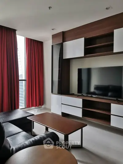 Modern living room with sleek furniture and large TV, featuring floor-to-ceiling windows and red curtains.