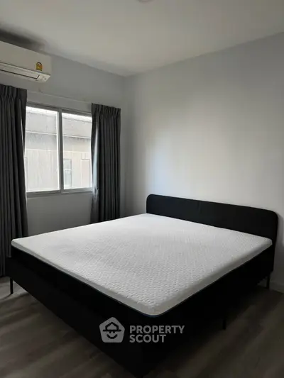 Modern bedroom with large window and minimalist design, featuring a comfortable bed and sleek flooring.