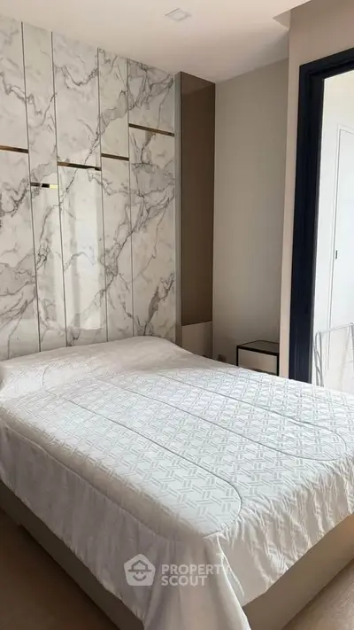 Luxurious bedroom with elegant marble accent wall and cozy bedding
