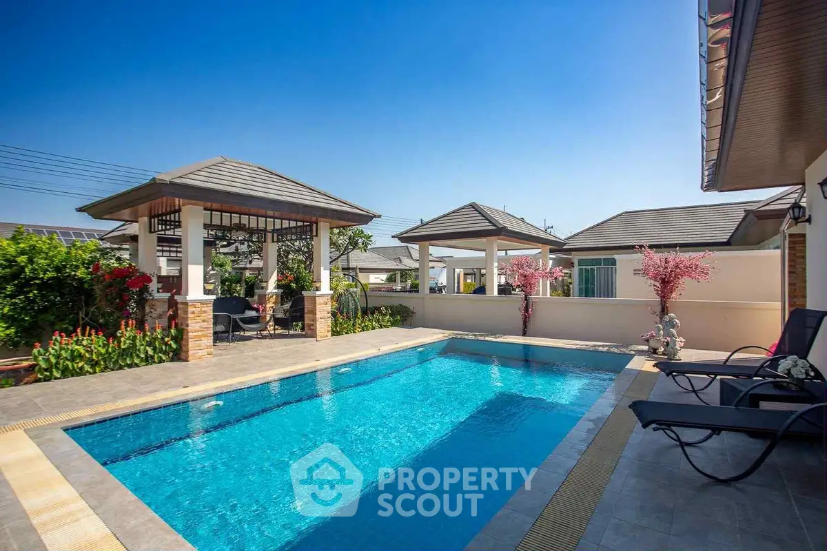 Luxurious outdoor pool area with shaded seating and vibrant garden landscaping.