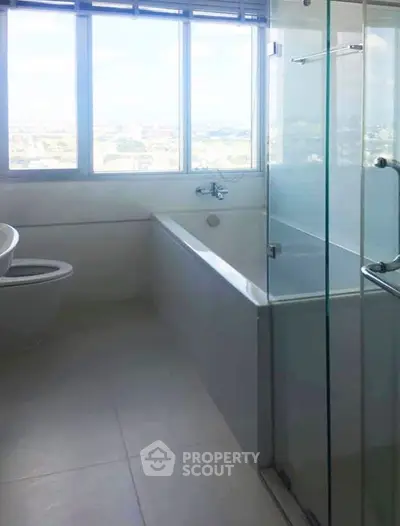 Modern bathroom with large window and bathtub offering city views.