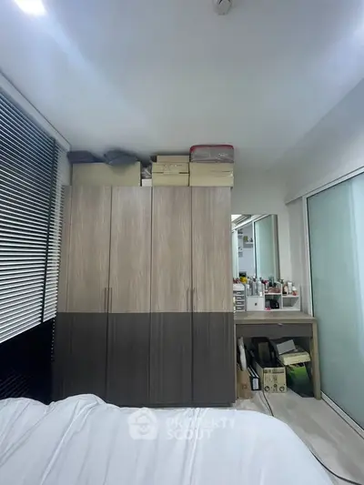 Cozy bedroom with modern wardrobe and organized vanity area, perfect for urban living.