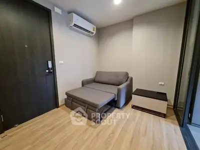 Modern living room with sleek sofa bed and air conditioning unit.