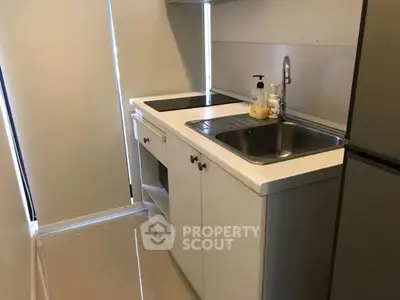 Compact kitchen with sleek white cabinetry and modern appliances