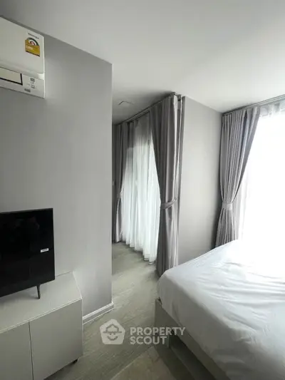 Modern bedroom with sleek design, featuring large windows and natural light, perfect for urban living.