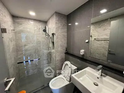 Modern bathroom with glass shower and sleek fixtures in contemporary apartment.