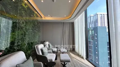 Luxurious modern lounge with floor-to-ceiling windows and city view, featuring elegant seating and greenery wall.