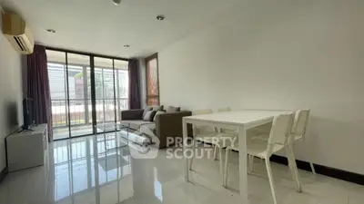 Modern living room with sleek furniture and large windows leading to a balcony.