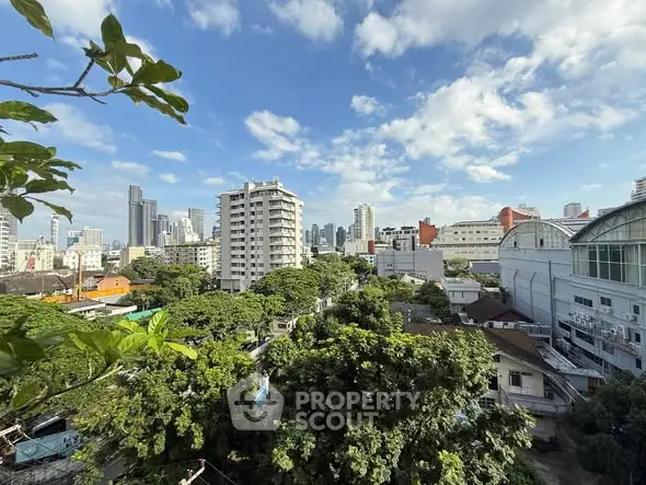 Stunning cityscape view with lush greenery and modern buildings under a clear blue sky.