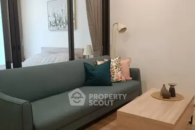 Modern living room with stylish sofa and decor, adjacent to a cozy bedroom.