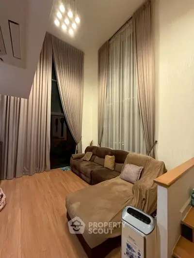 Spacious living room with high ceilings and elegant drapes, featuring a cozy sectional sofa.