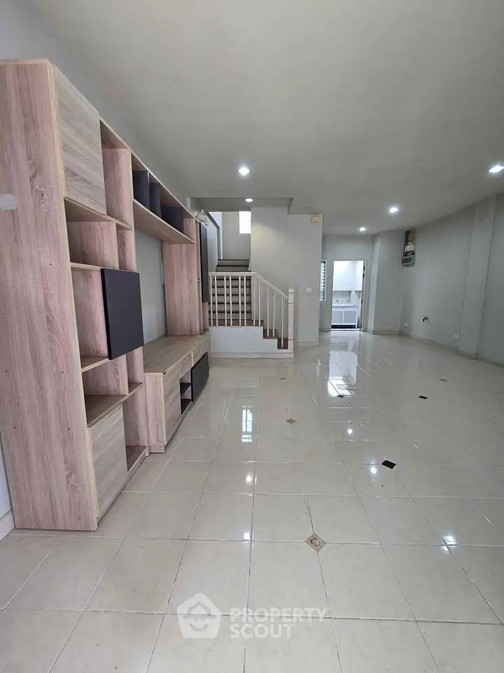 Spacious modern living room with sleek tile flooring and stylish wooden shelving unit.