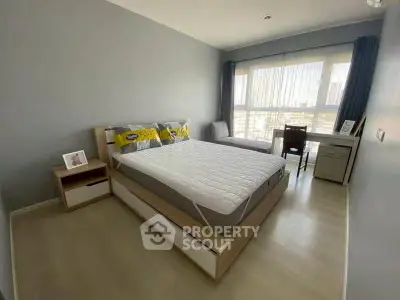 Spacious bedroom with modern decor and large window offering city views.