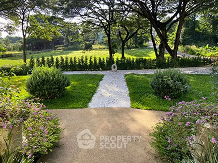 Charming garden view with lush greenery and stone pathway in serene setting.