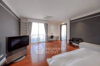 Spacious modern bedroom with hardwood floors and large windows in luxury apartment.