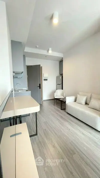 Modern living room with sleek kitchen and cozy seating area in a stylish apartment.