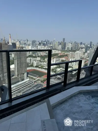 Stunning high-rise balcony view overlooking city skyline and sports field, perfect for urban living.