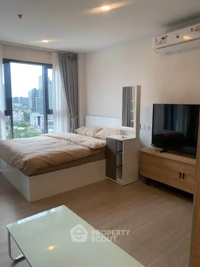 Modern bedroom with city view, featuring stylish furniture and large windows for natural light.