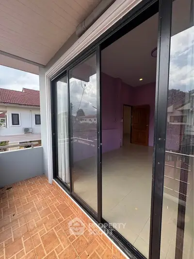 Spacious balcony with sliding glass doors and scenic neighborhood view