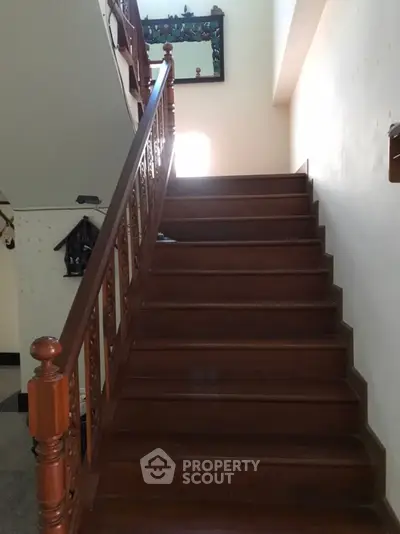 Elegant wooden staircase with decorative railing in a well-lit home interior