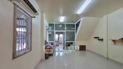 Spacious living room with modern staircase and large window, perfect for family gatherings.