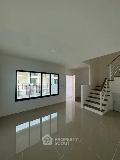 Spacious modern living room with sleek staircase and large window view