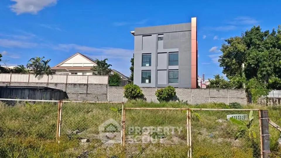 Modern building exterior with lush greenery and clear blue sky