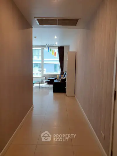 Spacious hallway leading to a modern living room with large windows and stylish decor.