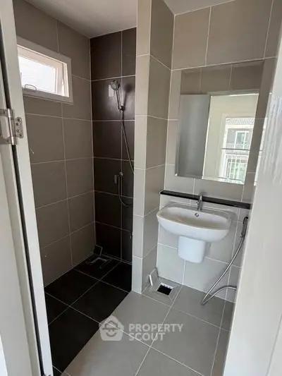 Modern bathroom with sleek tiles and a compact shower area, perfect for contemporary living.